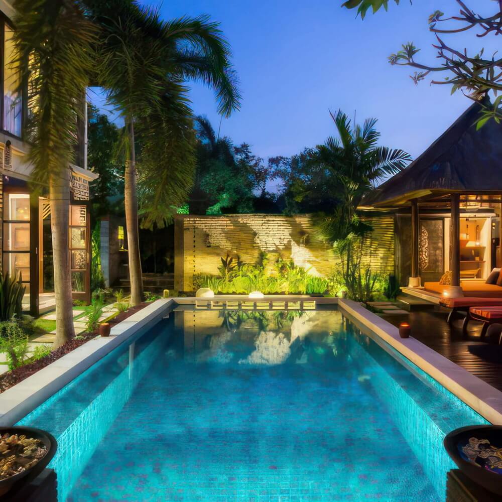 The pool illuminated at night with the traditional balé beside it