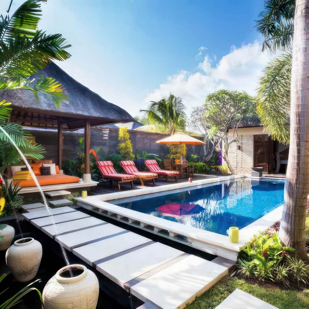 The private pool and traditional thatched balé under blue skies