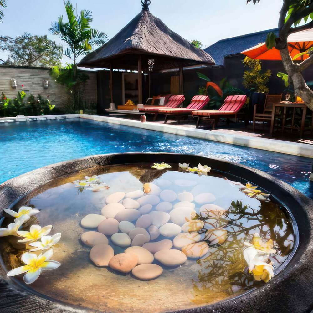 Frangipani flowers floating in a stone bowl beside the pool