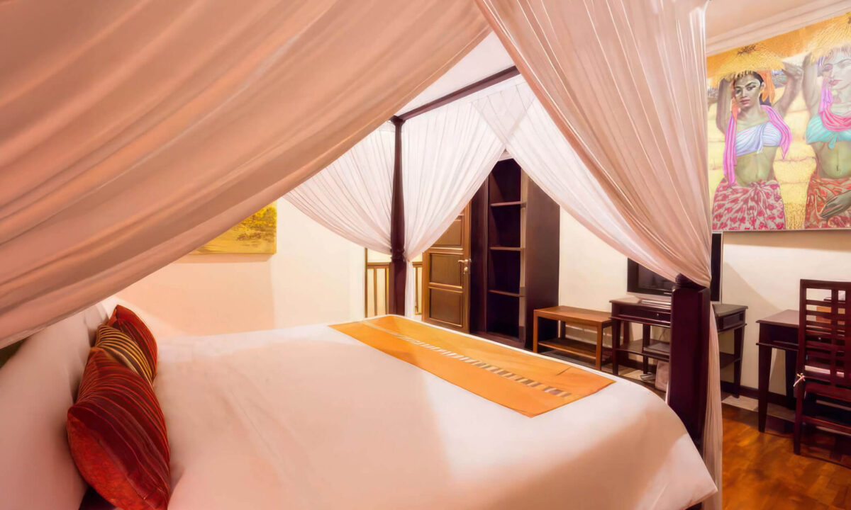 An upstairs king-size four-poster bedroom with Balinese art and warm timber details